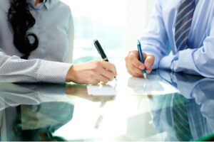 Two people sitting and signing an agreement